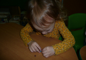 dziewczynka nawleka koralik na sznureczek