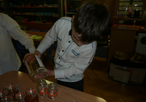 chłopczyk nalewa miód do słoiczka
