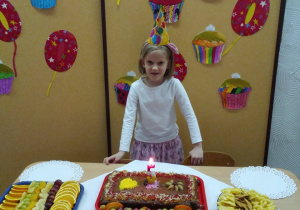 dziewczynka na tle dekoracji urodzinowej przy cieście i zdrowych przekąskach