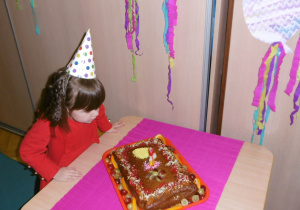 dziewczynka na tle dekoracji urodzinowej przy cieście i zdrowych przekąskach