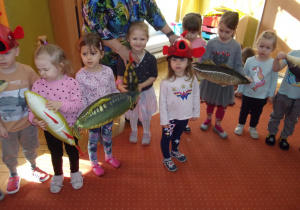 Tuptusie podczas koncertu na sali gimnastycznej trzymają w rękach zabawkowe ryby