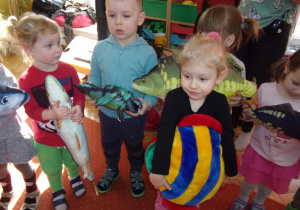 Tuptusie podczas koncertu na sali gimnastycznej trzymają w rękach zabawkowe ryby