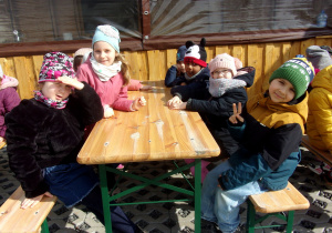 Juniorzy siedzą przy drewnianych ławeczkach