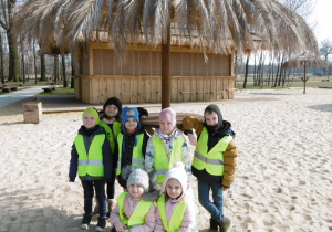 Żaczki - dzieci stoją pod parasolem na piasku