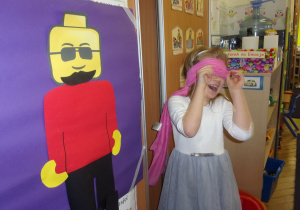 dziewczynka przykłada elementy klocka lego z zamkniętymi oczami