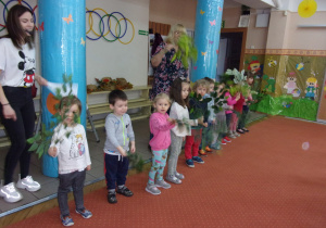 dzieci z listkami w rączkach ustawione w szeregu na sali gimnastycznej