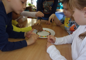 dzieci układją cukierki na talerzyku