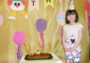 dziewczynka w czapeczce urodzinowej przy torcie