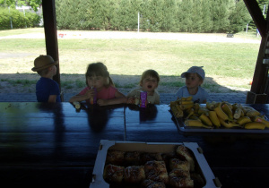 Tuptusie i Smyki przy stole piją soczek i jedzą bułkę słodką oraz banana
