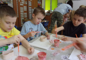 Juniorzy malują farbami wczesniej uformowane szkatułki z gliny
