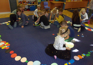 Juniorzy podczas zabawy z kropkami na dywanie