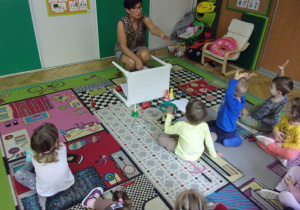 zajęcia logorytmiczne w Tuptusiach - dzieci siedzą na dywanie i odgadują jaki przedmiot wydaje dźwięk