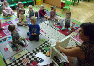 zajęcia logorytmiczne w Tuptusiach - dzieci siedzą na dywanie i odgadują jaki przedmiot wydaje dźwięk