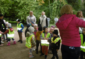 dzieci w kamizelkach odblaskowych podczas spaceru po arboretum