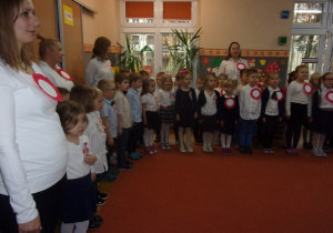 przedszkolaki ubrane na galowo śpiewają hymn na sali gimnastycznej