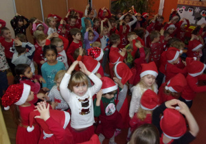 dzieci ubrane na czerwono na sali gimnastycznej śpiewają piosenkę w oczekiwaniu na Mikołaja