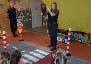 Strażnik Miejski opowiada dzieciom o sygnalizacji wskazując czerwone światło