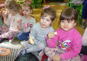 dziewczynki jedzą jabłka na dywanie
