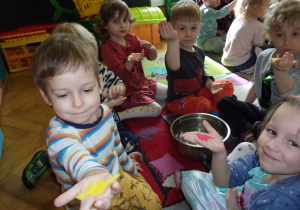 dzieci trzymają w rączkach gąbkowe dinozaury w kolorze żółtym i różowym