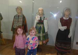 dwie dziewczynki na tle ekspozycji muzealnej - stroje ludowe