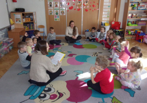 Smyki na dywanie ze studentami słuchają czytanej bajki