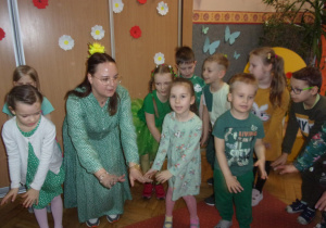 dzieci ubrane na zielono na sali gimnastycznej uczestniczą w zabawach tanecznych