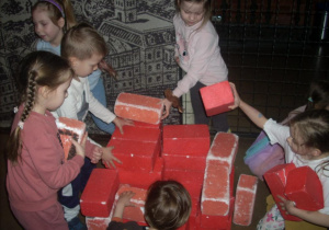 dzieci układają czerwone cegły, budują komin fabryczny