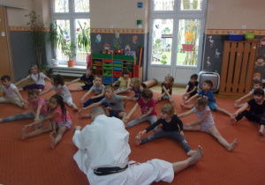 Juniorzy siedzą na dywanie podczas zajęć Karate