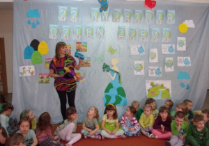 ciocia Ola tłumaczy dzieciom kolejne zadanie do wykoanania na tle dekoracji z okazji Dnia Ziemi