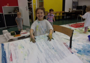 dziewczynka w białej podkoszulce maluje na arkuszach białego papieru