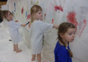 dzieci w białych koszulkach malują farbami plakatowymi