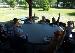 dzieci przy okrągłych stołach jedzą zupę z soczewicy z boczkiem i ziemniakami