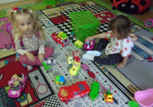 dwie dziewczynki bawią się na dywanie