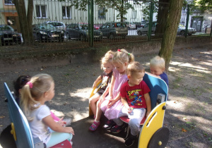 grupka dzieci na samochodziku w ogrodzie przedszkolnym