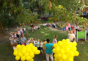 dzieci ze wszystkich grup w kole uczestniczą w zabawach z okazji Dnia Przedszkolaka w ogrodzie przedszkolnym