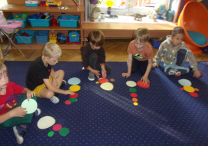 Juniorzy na dywanie ukłądają kompozycje z kropek dużych i małych