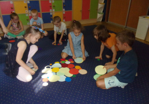 Juniorzy na dywanie ukłądają kompozycje z kropek dużych i małych