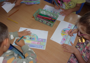 Juniorzy przy stolikach kolorują obrazki tamatycznie związane z Dniem Kropki