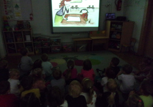 Smyki i Tuptusie na dywanie oglądają prezentację na tablicy interaktywnej