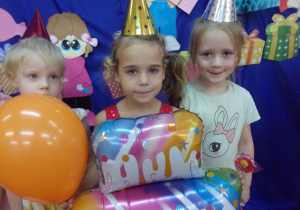trzy dziewczynki na tle dekoracji urodzionowej