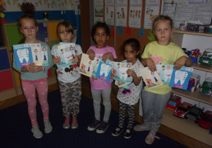 dziewczynki prezentują książeczki "Dziel się uśmiechem"