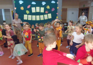 dzieci ze wszystkich grup wiekowych tańczą na sali gimnastycznej, w tle dekoracji z okazji Balu Jesieni