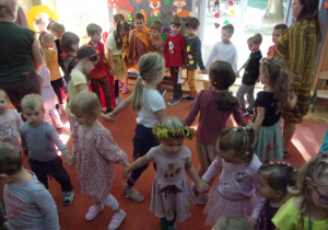 dzieci w kołąch tańczą na sali gimnastycznej w przebraniach z okazji Balu Jesieni