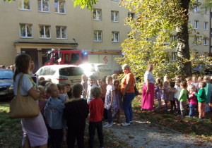 dzieci z poszczególnych grup ustawione przed przedszkolem, w tle wóz strażacki