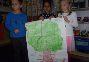 trójka dzieci przedstawia pracę wykonaną grupowo