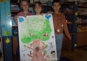 trójka dzieci przedstawia pracę wykonaną grupowo