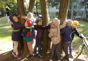 kilkoro dzieci w ogrodzie przedszkolnym na tle drzew