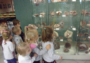 dzieci oglądają ekspozycje za szklanymi gablotami