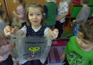 dziewczynka pokazuje torebkę z nazbieranymi niespodziankami
