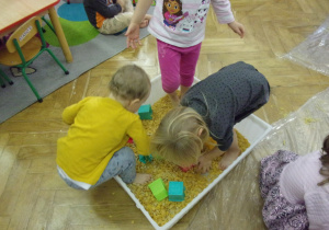 troje dzieci bawi się w płatkach kukurydzianych